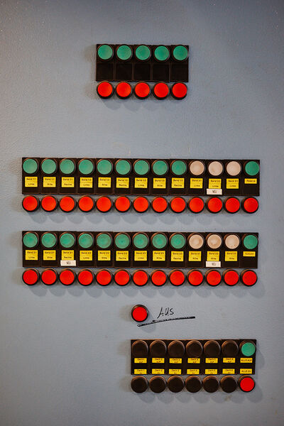 Schalttafel mit mehreren grünen und roten Knöpfen sowie gelben Beschriftungen