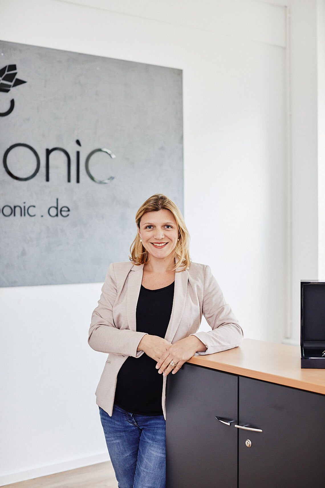 Sabine Linz, Gründerin von amoonic.de, lehnt in Büro an einem Regal