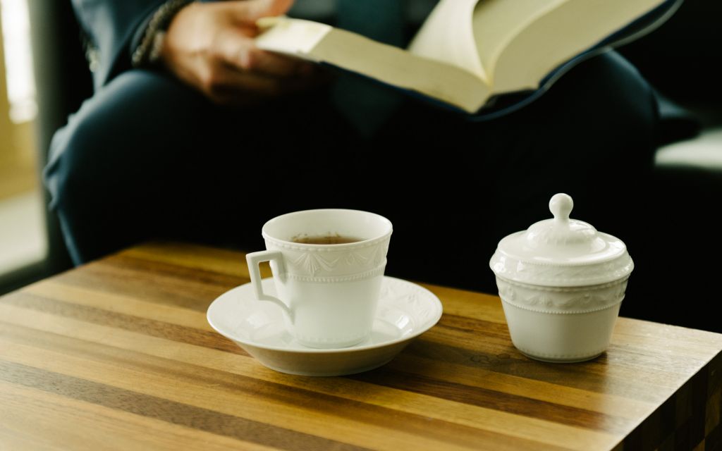 Weiße Zuckerdose und Porzellantasse aus der KPM-Serie Kurland stehen auf Holztisch