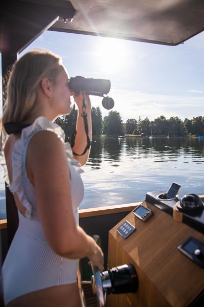 Junge Frau am Steuer eines E-Boots schaut durch Fernglas