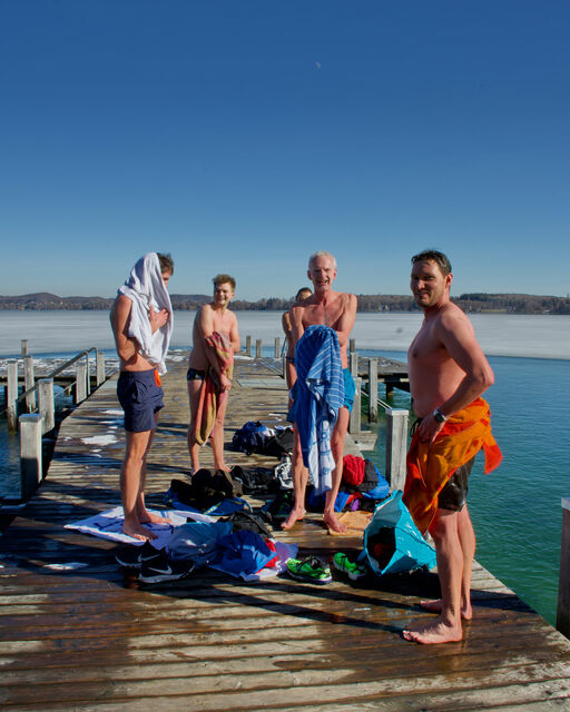 Die Winterschwimmer trocknen sich nach der Schwimmrunde auf dem Steg bei Sonnenschein ab