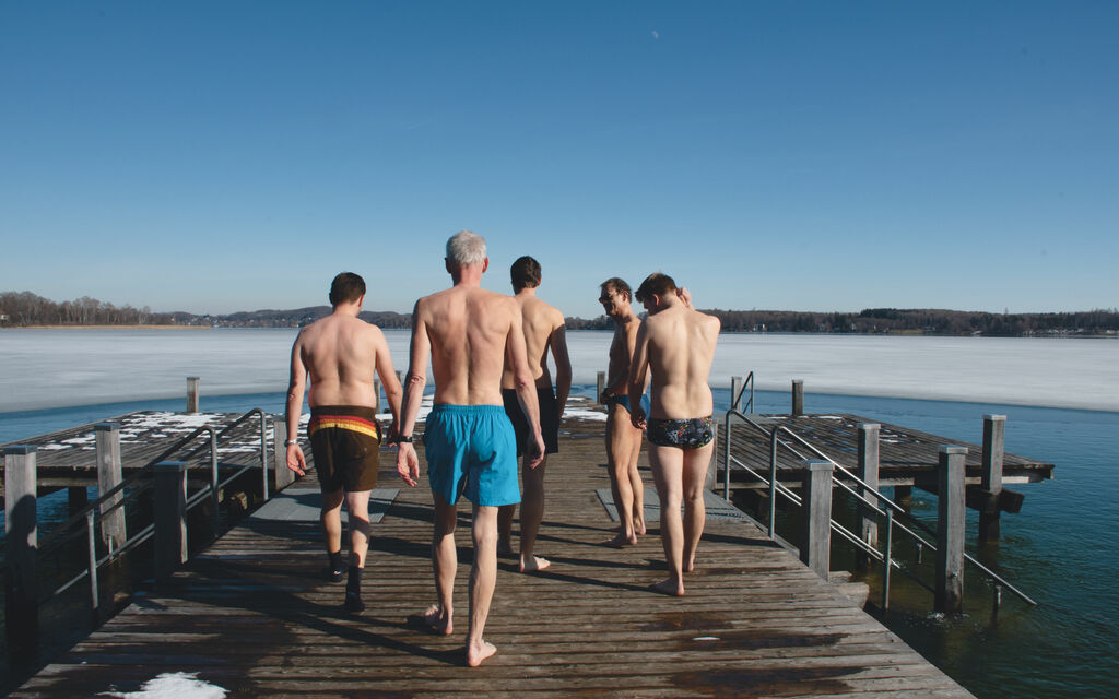 Die Winterschwimmer gehen in Badebekleidung den Steg des Wörthsees entlang