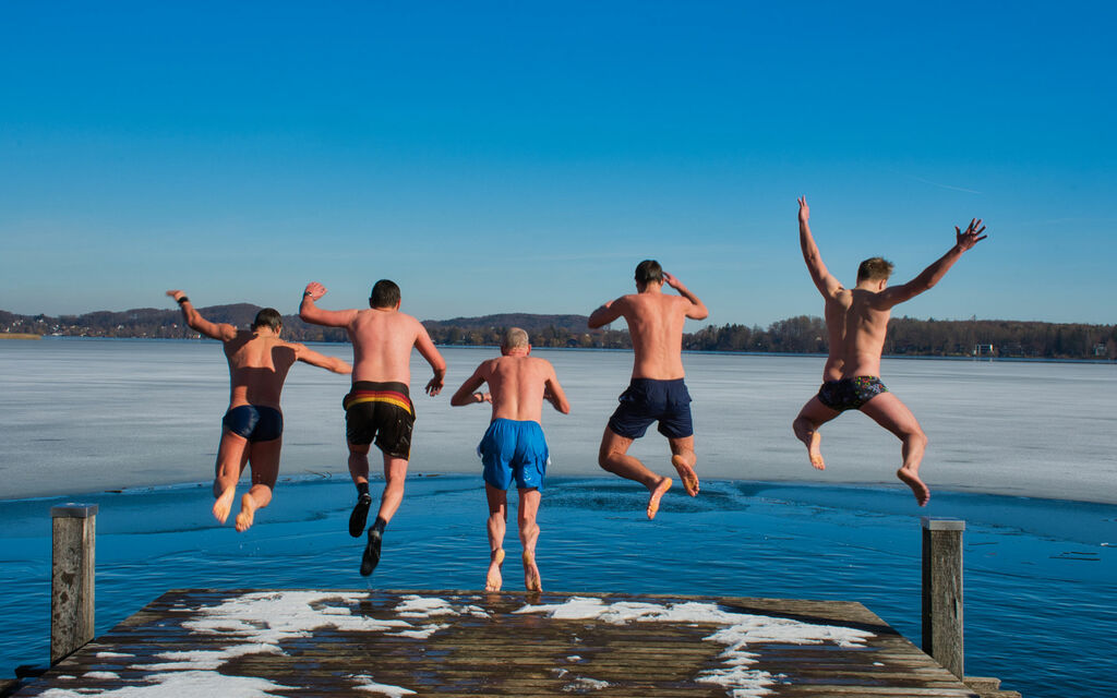 The winter swimmers jump together from the jetty into the lake