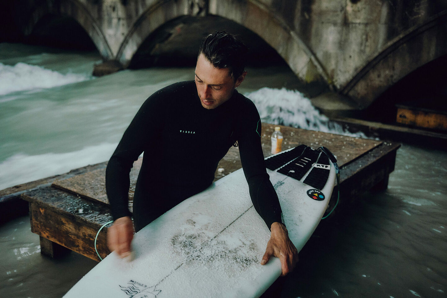 Sebastian Kuhn bereitet sein Surfbrett mit Wachs vor