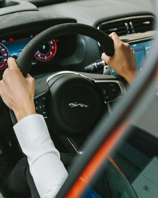 Nahaufnahme des Cockpits eines Jaguar-Rennautos und Célia Martins Händen am Lenkrad