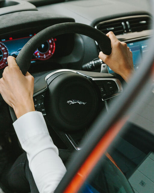 Close-up of the cockpit of a Jaguar racing car and Célia Martin's hands on the steering wheel