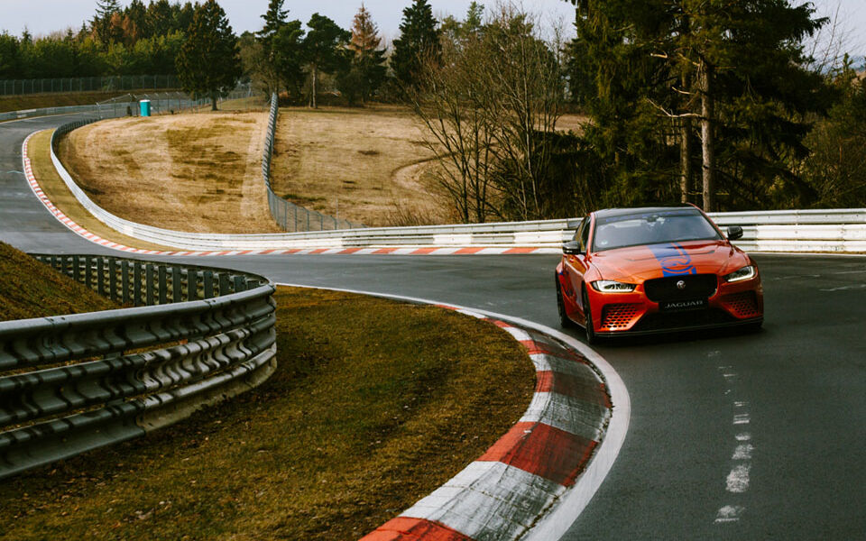 Orange-blue Jaguar in a bend at the Nürburgring