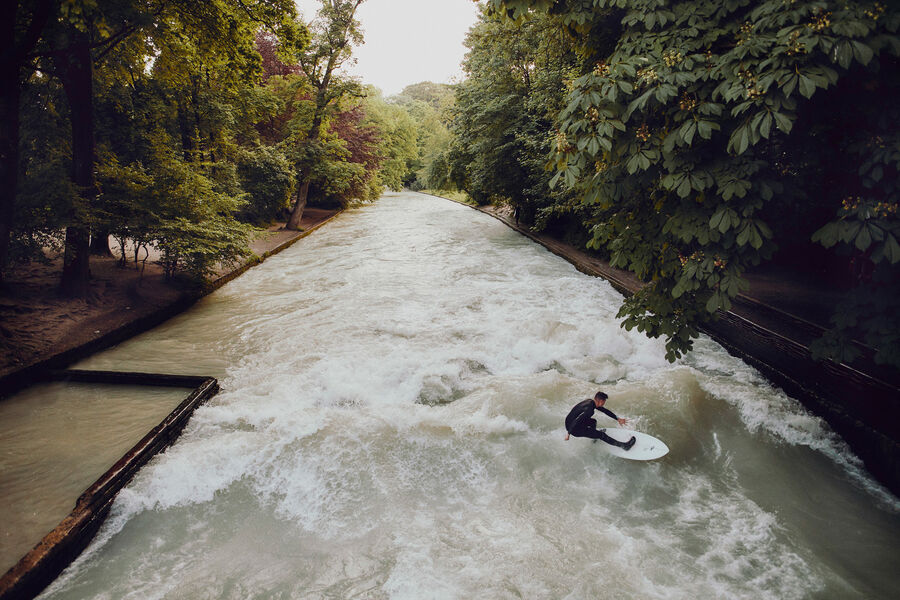 Der Münchner Eisbach mit seiner Welle und einem Surfer