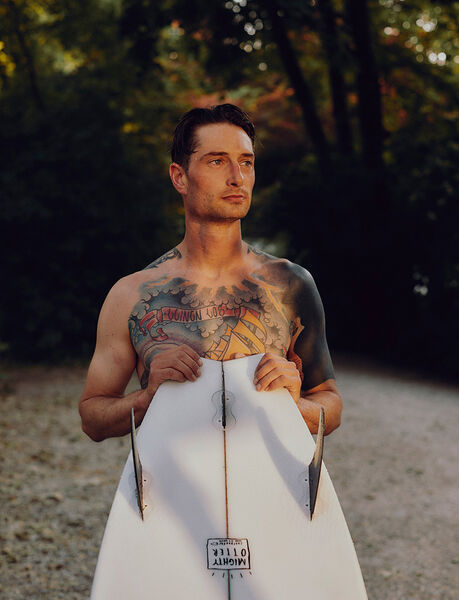 Surfer Sebastian Kuhn with his surfboard in front of his body