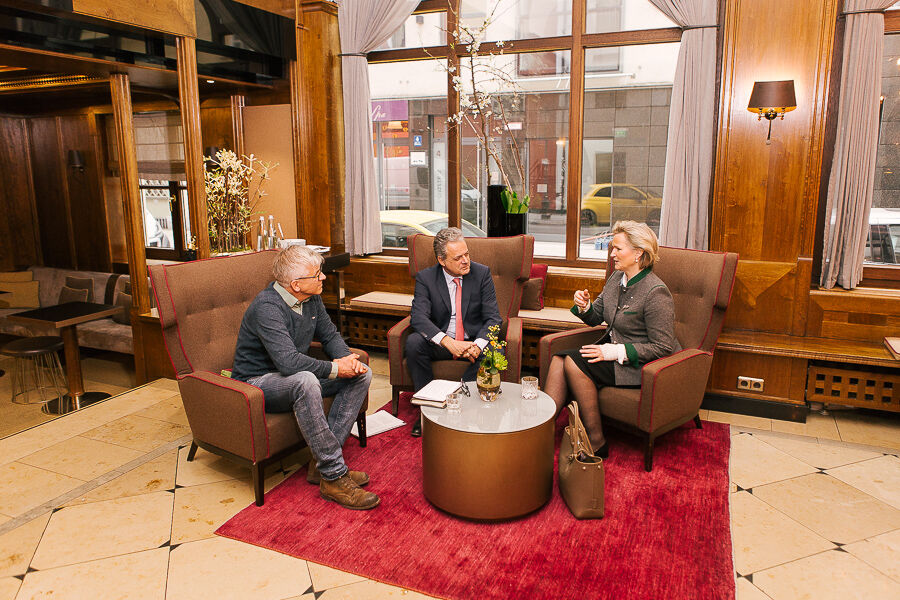Stefan Ruzas, Harald Pechlaner and Angela Inselkammer talking in the lobby of a hotel in Munich