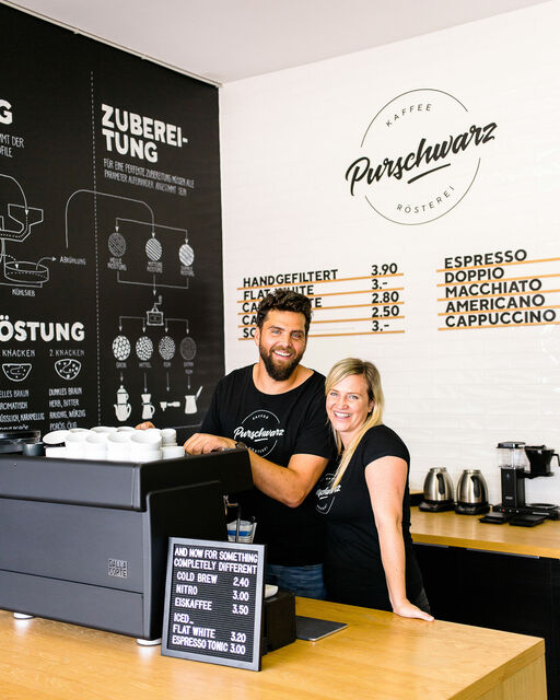 Alexander und Andrea, die Gründer von Purschwarz, stehen in ihrer Kaffeebar