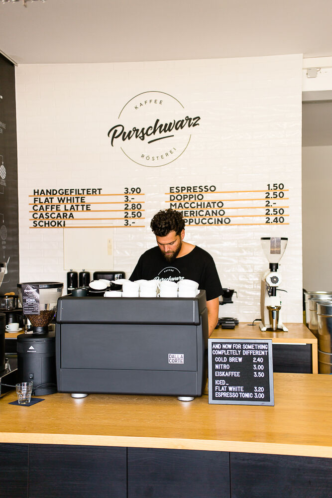 Alexander Gourgius stands at the counter of his coffee shop and prepares a cup of coffee
