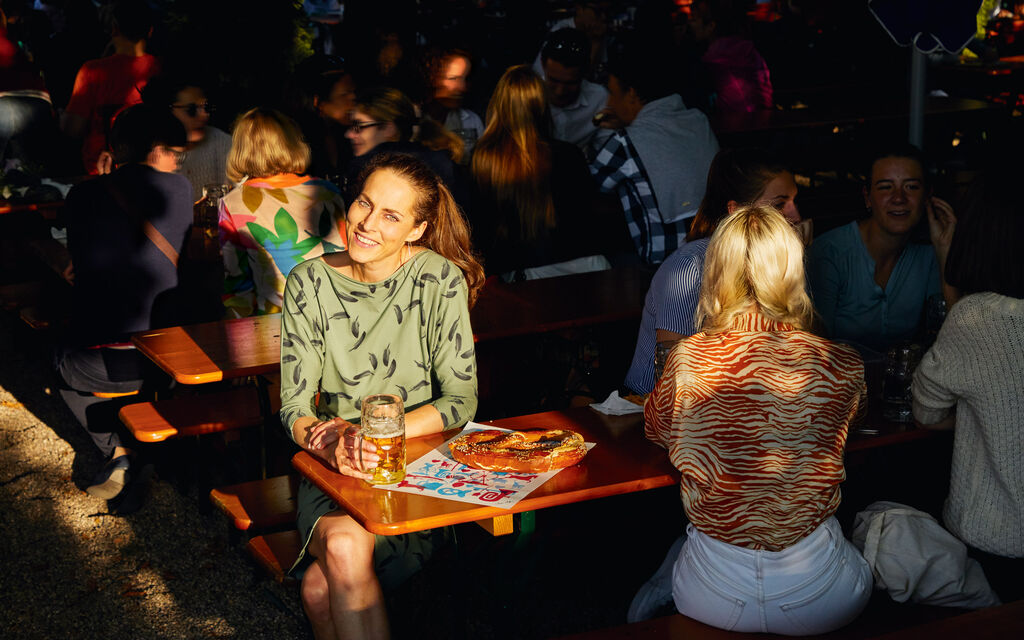 Mirjam Mössmer wearing a green patterned dress is sitting in the beer garden