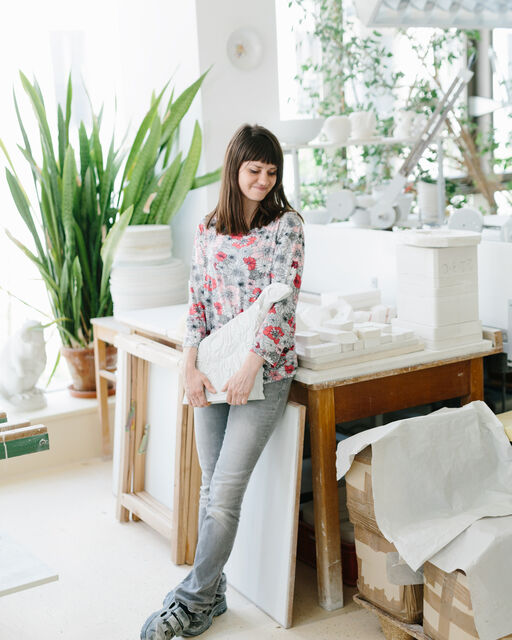 KPM employee Anja Sonn leans at the table and holds a porcelain sheep in her hands