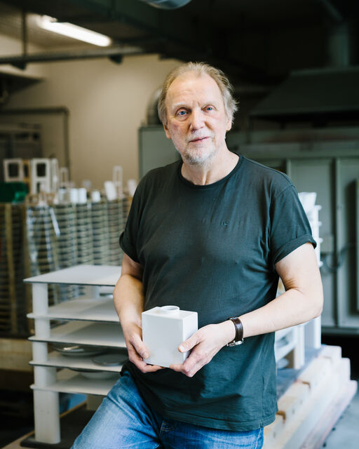 KPM-Mitarbeiter Bernhard Quapp mit einer weißen KPM CADRE Vase in Händen in der Werkstatt stehend