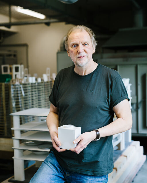 KPM employee Bernhard Quapp standing in the factory with a white KPM CADRE vase in his hands