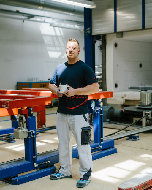 KPM employee Markus Uhlig standing in the factory with a white KPM breakfast cup