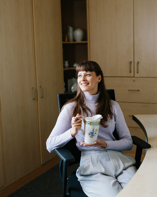 KPM employee Marleen Haman sitting at her office desk with a painted KURLAND water jug in her hands