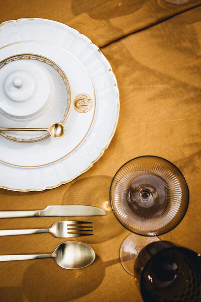 Gedeck mit Tellern, Besteck und Gläsern auf einer gelben Tischdecke