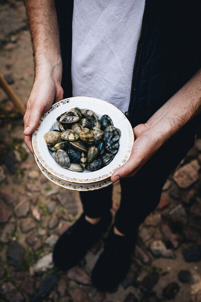 Mann hält einen Teller mit Muscheln in der Hand