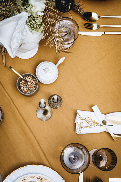 Aufnahme der gedeckten Tafel von oben mit Gläsern, Besteck, Kerzen und einer kleinen Schale mit Pinienkernen