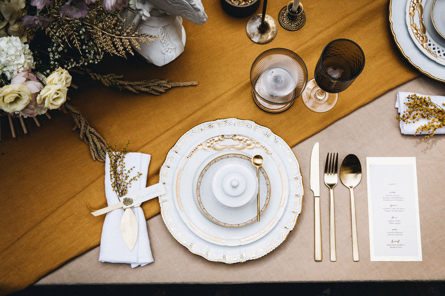 Fertiges Gedeck mit Tellern, Besteck und Gläsern auf dem Tisch von oben aufgenommen