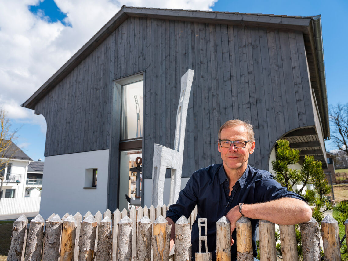 Hans Panschar is leaning against the fence in front of his house