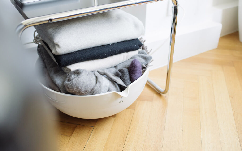 Blankets in a big KPM steam bowl stored on the floor under a chair