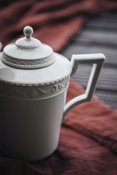 Close-up of a teapot from the KURLAND collection by KPM on a red picnic blanket on the jetty