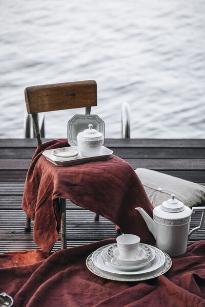 KPM tableware from the KURLAND series draped on a red picnic blanket on the jetty