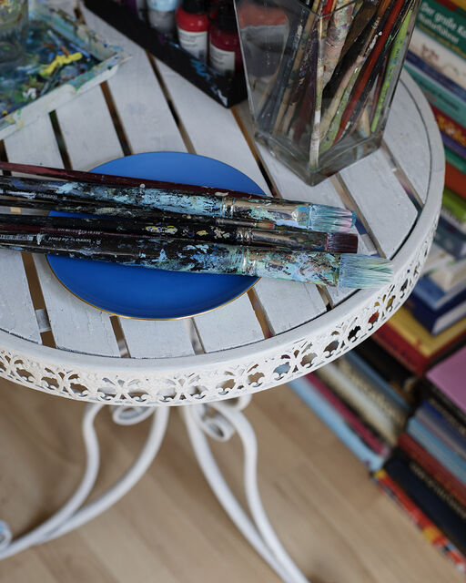 Brushes covered with paint lie on a small round white table