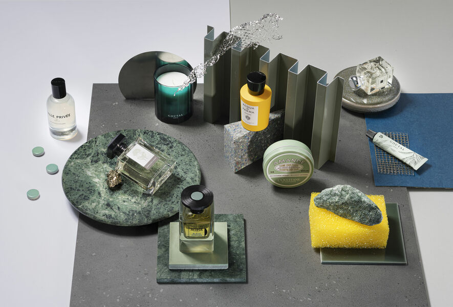 Still life with green and yellow beauty products on marble plates and surfaces in grey and blue