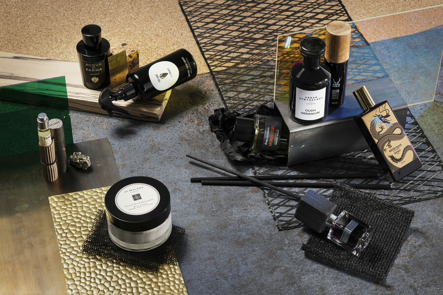 Still life with various perfumes, body lotions and creams on golden and grey surfaces