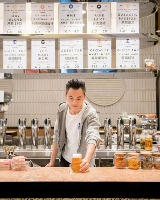 Chinesischer Barkeeper stellt ein Glas Bier auf Bartresen
