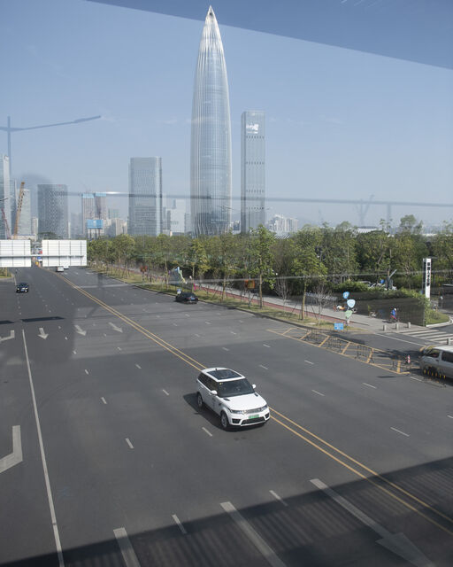 Weißer Range Rover Sport Plug-in Hybrid fährt mehrspurige Straße vor Skyline der Stadt Shenzhen entlang