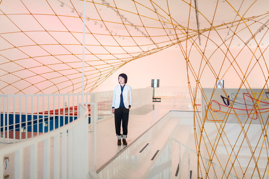 Rong Zhao, stellvertretende Direktorin der Design Society, steht in Raum mit gitterförmigen Designelementen