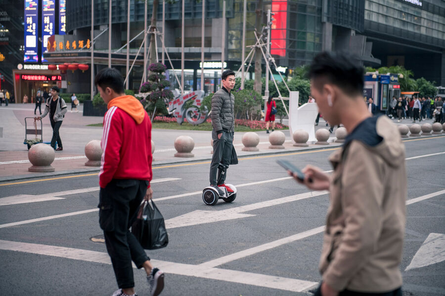 Momentaufnahme mehrerer Fußgänger und eines Hoverboard-Fahrers auf Straße in Shenzhen