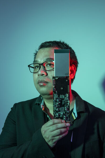Blue-exposed portrait photo of the Chinese investor Robin Wu holding electric circuit board