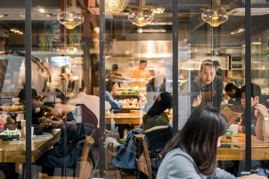 View through window front into an Asian restaurant with numerous guests