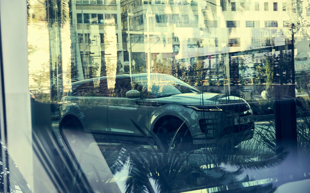 Range Rover Evoque spiegelt sich in einer Fensterscheibe in einem Wohnviertel in Athen