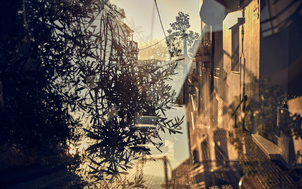 Olive trees and alleyway in Athens residential area reflected in windshield of Range Rover Evoque