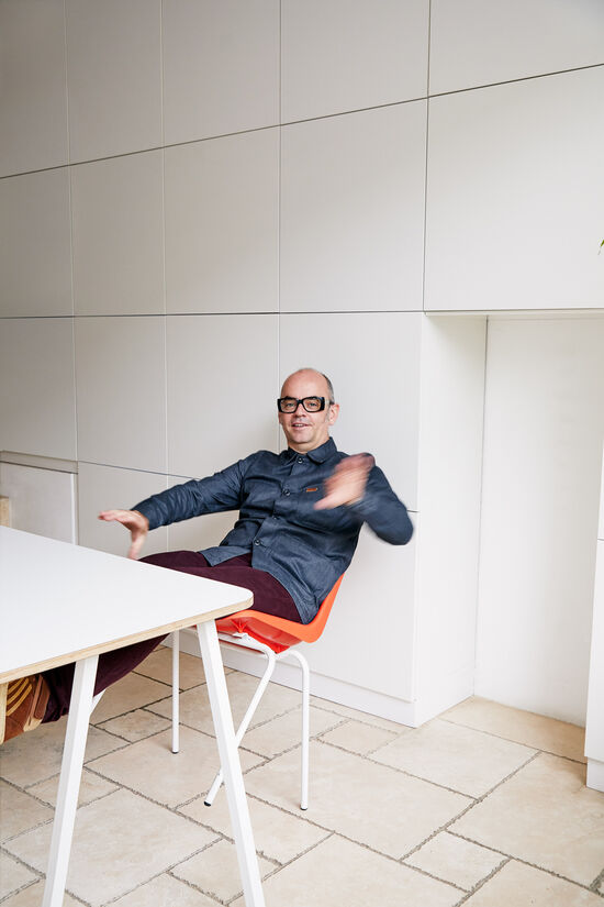 Roller coaster engineer Brendan Walker sits on an orange chair and looks into the camera