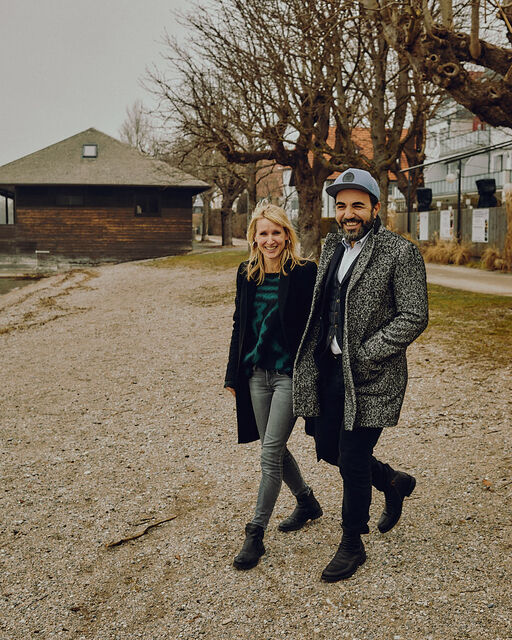 Franziska and Adnan Maral walk on a pebble beach on the shore of the Ammersee