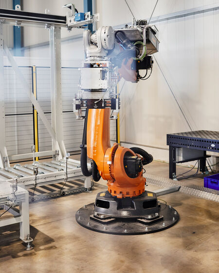 Orangefarbener Industrieroboter steht in Fertigungshalle des Unternehmens Main-Automation