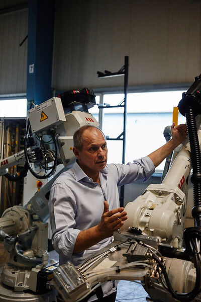 Man stands between industrial robots and explains their function