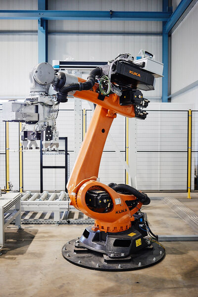 Orange-coloured industrial robot in production hall of Main-Automation