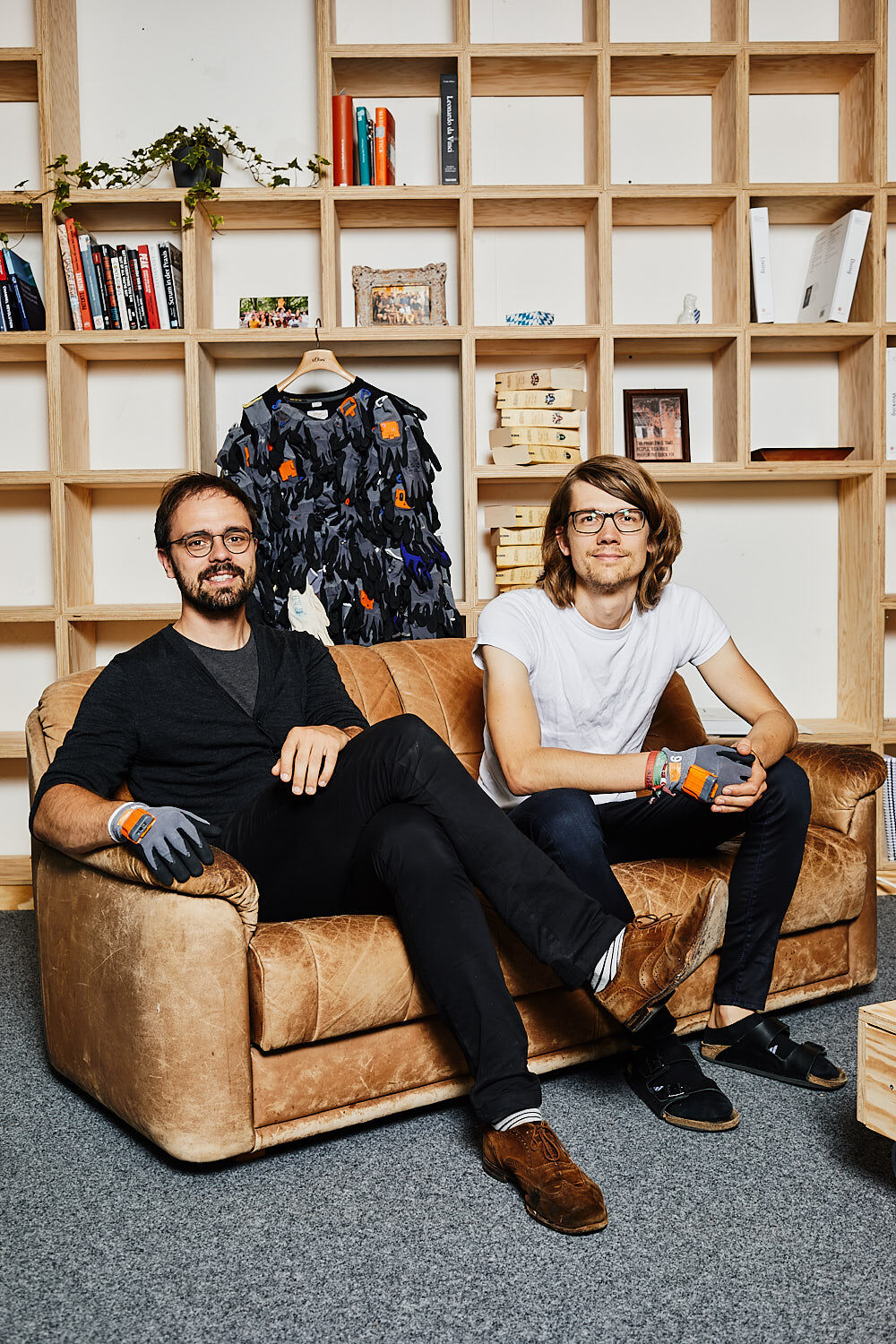 Thomas Kirchner and Paul Günther, founders of Proglove, sitting on a leather sofa in front of a bookshelf