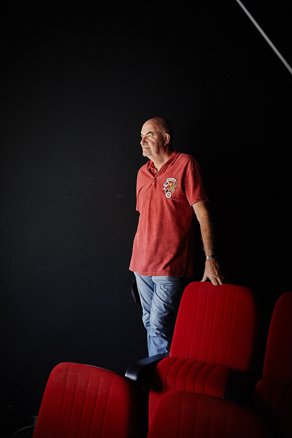 Thomas Zauner, founder of Scanline, leans against a red cinema chair in the cinema auditorium