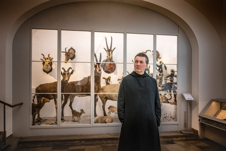 Monk of the Archabbey of Saint Ottilien stands in front of a showcase with stuffed mountain animals