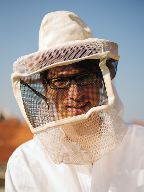 Portrait photo of policeman Jürgen Brandl with a beekeeper mask over his head